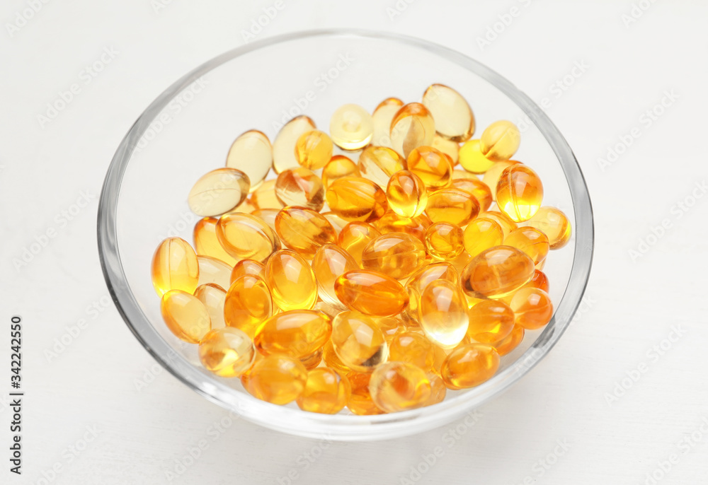 Bowl with fish oil capsules on table