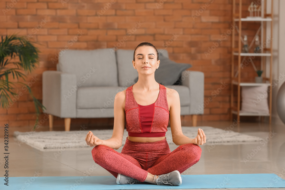 Sporty young woman practicing yoga at home