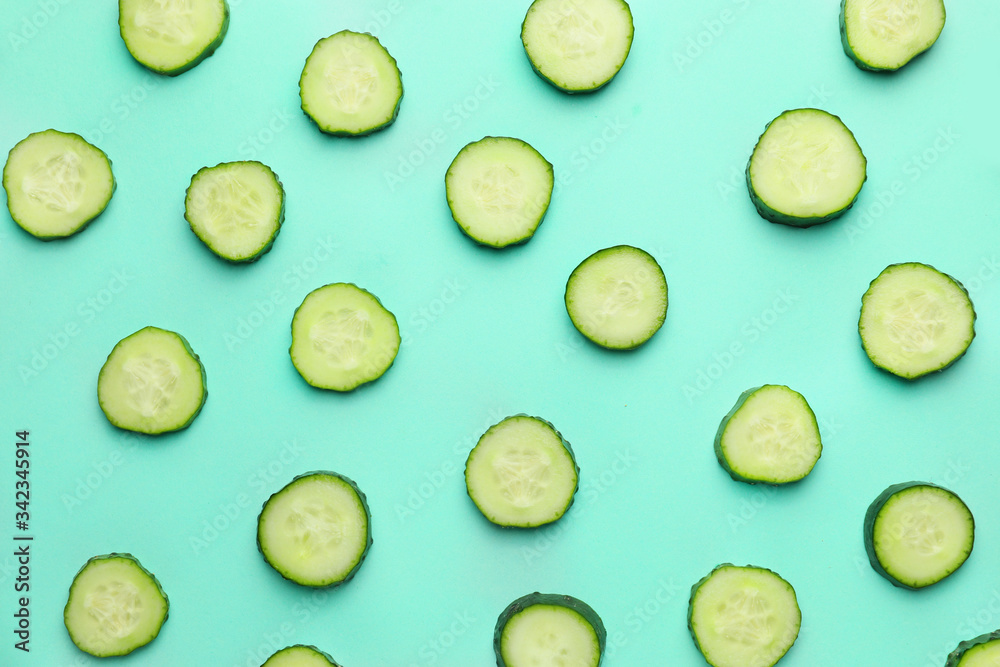 Green cut cucumbers on color background