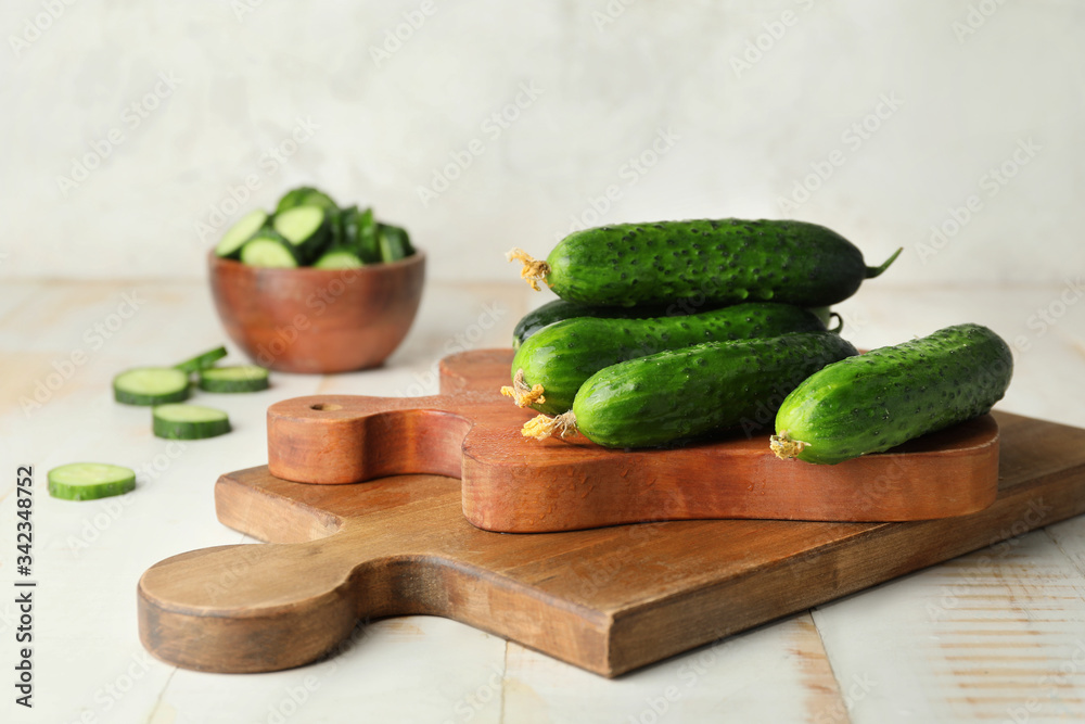 Board with green cucumbers on table