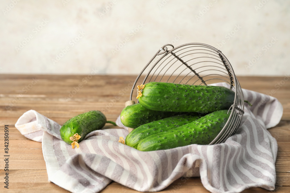 Basket with green cucumbers on wooden table