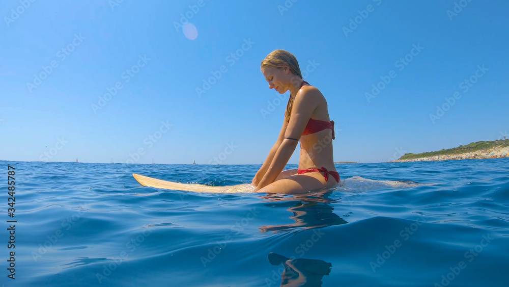 特写：美丽的女冲浪者坐在冲浪板上排队等候