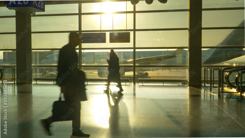 SILHOUETTE Unrecognizable tourists hurry up and down Frankfurt airport at sunset