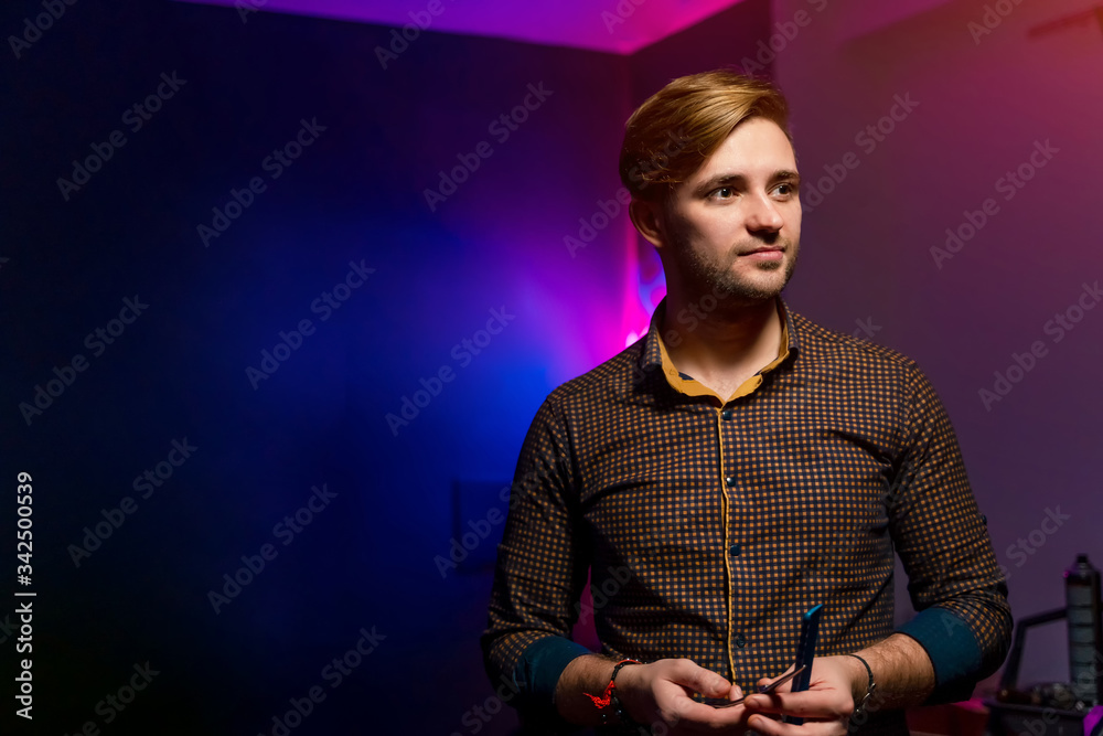 Handsome man standing and looking aside. Slim man with modern haircut.