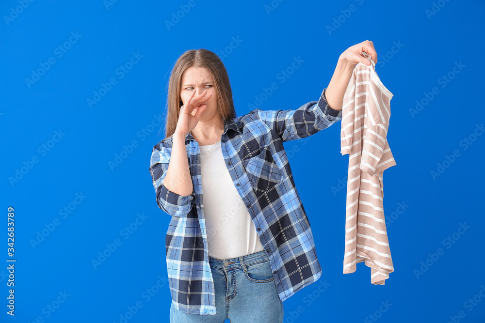 Displeased woman with dirty clothes on color background