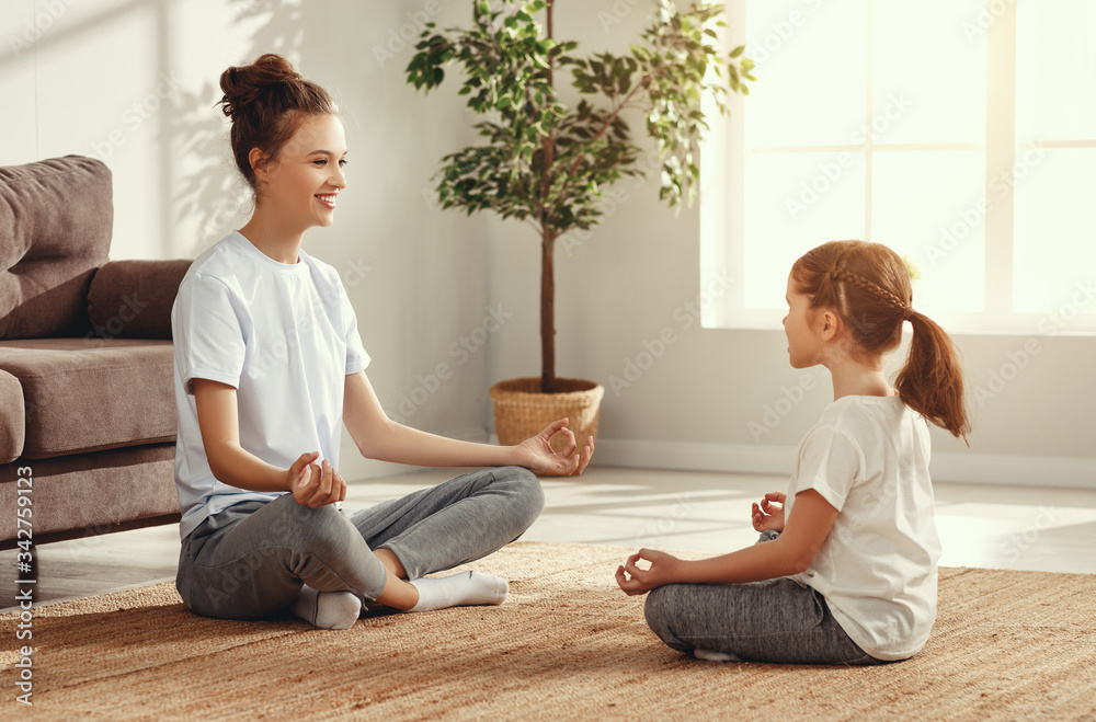 Mother and daughter meditating in living room