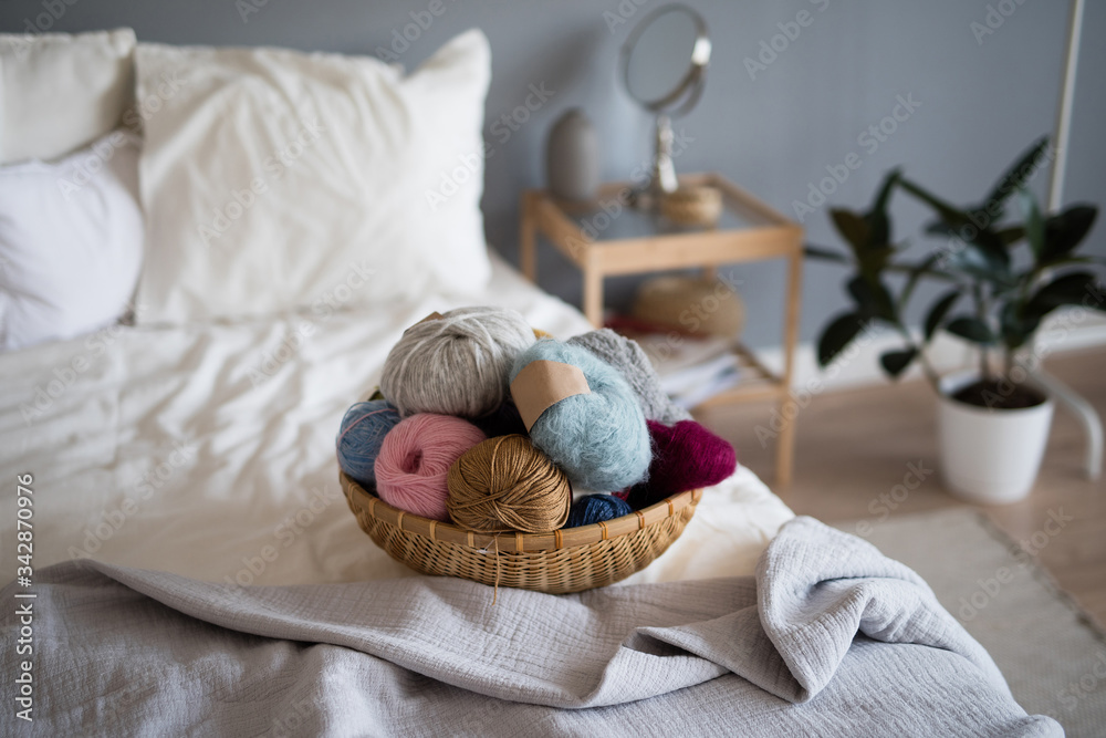 basket with yarn lies on a white bed