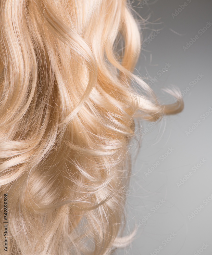 Blond Hair. Beautiful healthy long curly blonde hair close-up texture. Dyed Wavy white hair backgrou