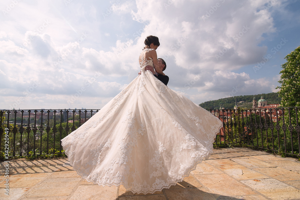 newlyweds, the groom circles the bride in her arms, a train to fly scatters