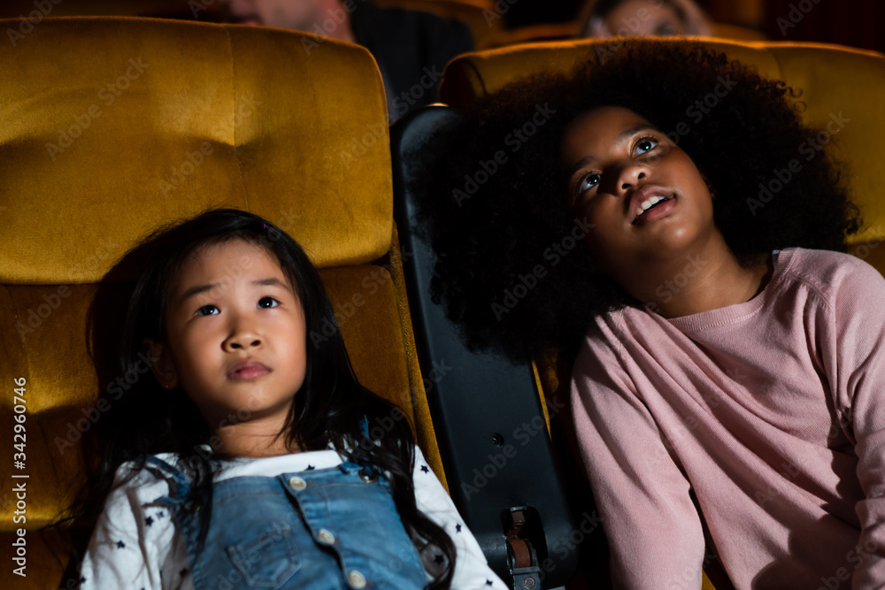 Two children african and asian having fun and enjoy watching movie in cinema