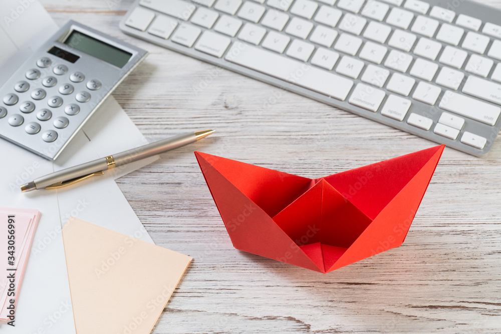 Top view office workspace with red paper ship