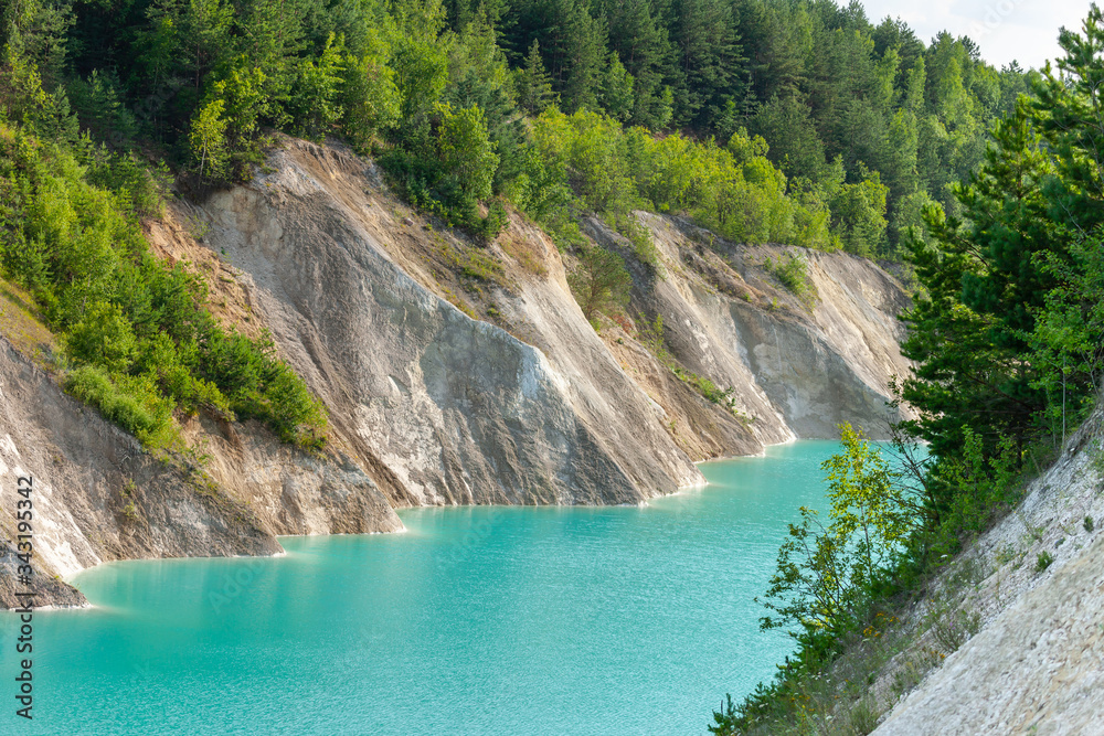 Turquoise river between small mountains with forest. Amazing summer landscape with blue sky and whit