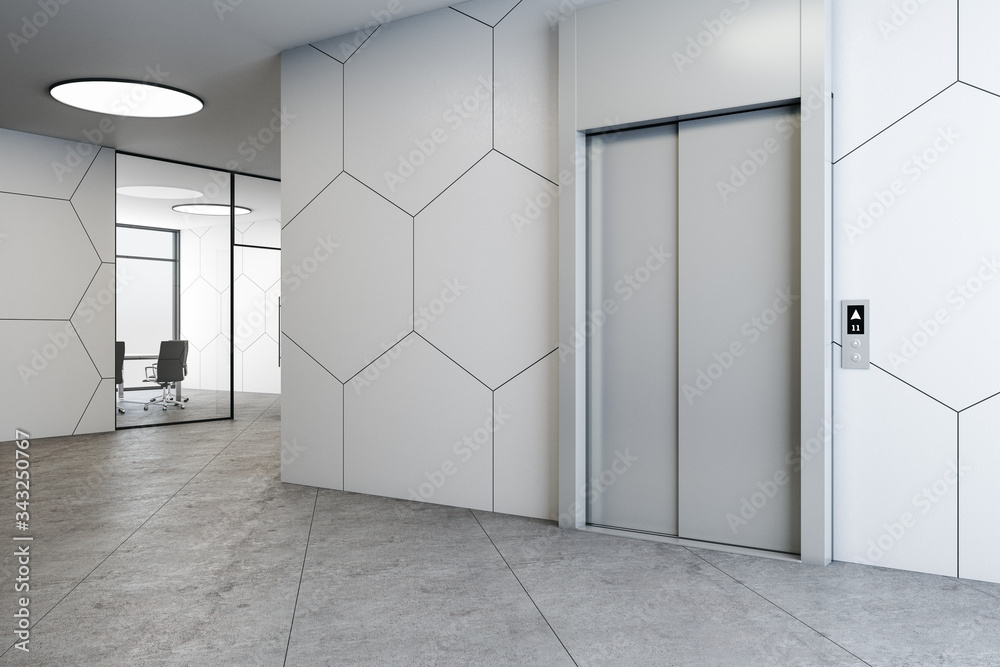 Modern office interior with elevators and concrete floor.