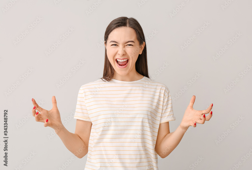 Portrait of screaming young woman on grey background