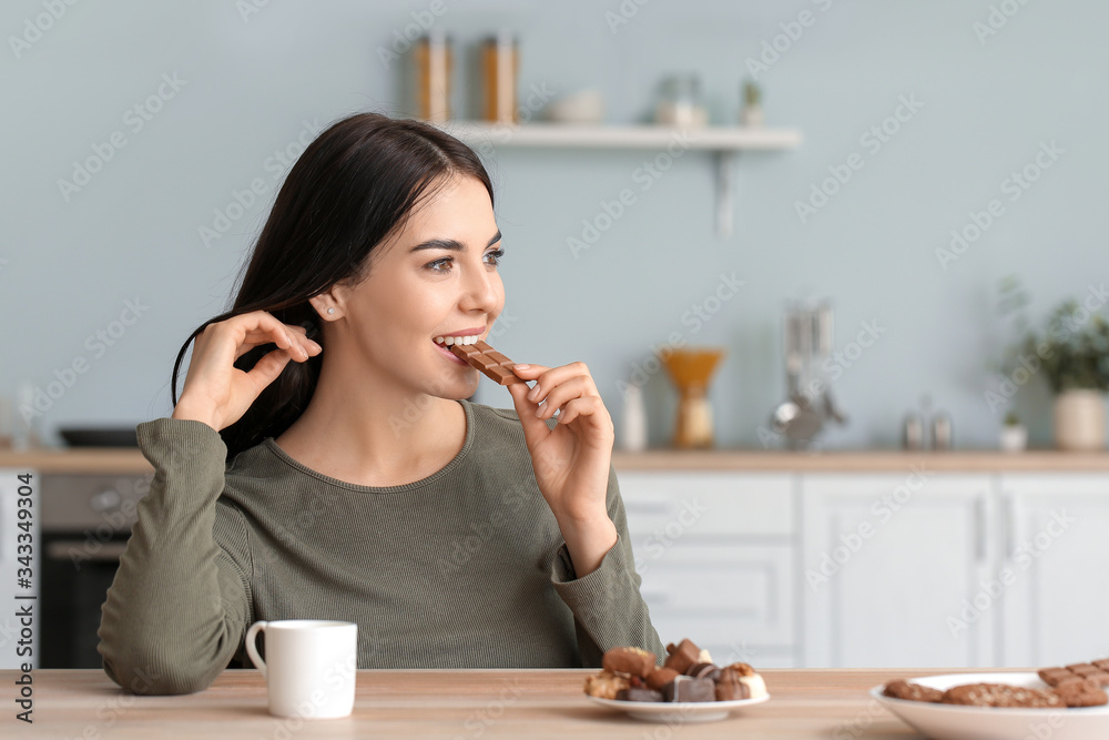 美丽的年轻女子在厨房吃巧克力