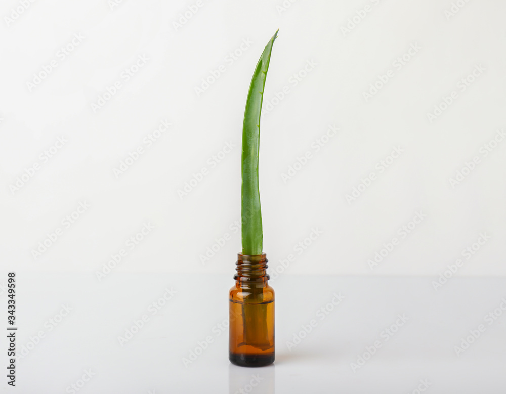 Bottle with aloe essential oil on white background