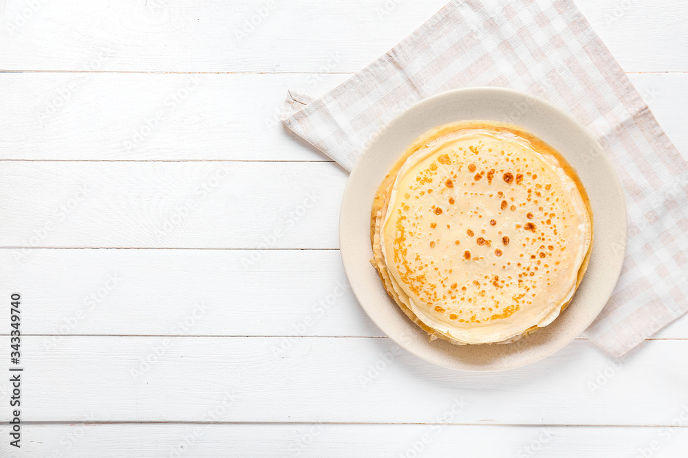 Plate with tasty blini on table