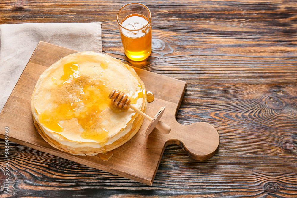 Tasty blini with honey on table