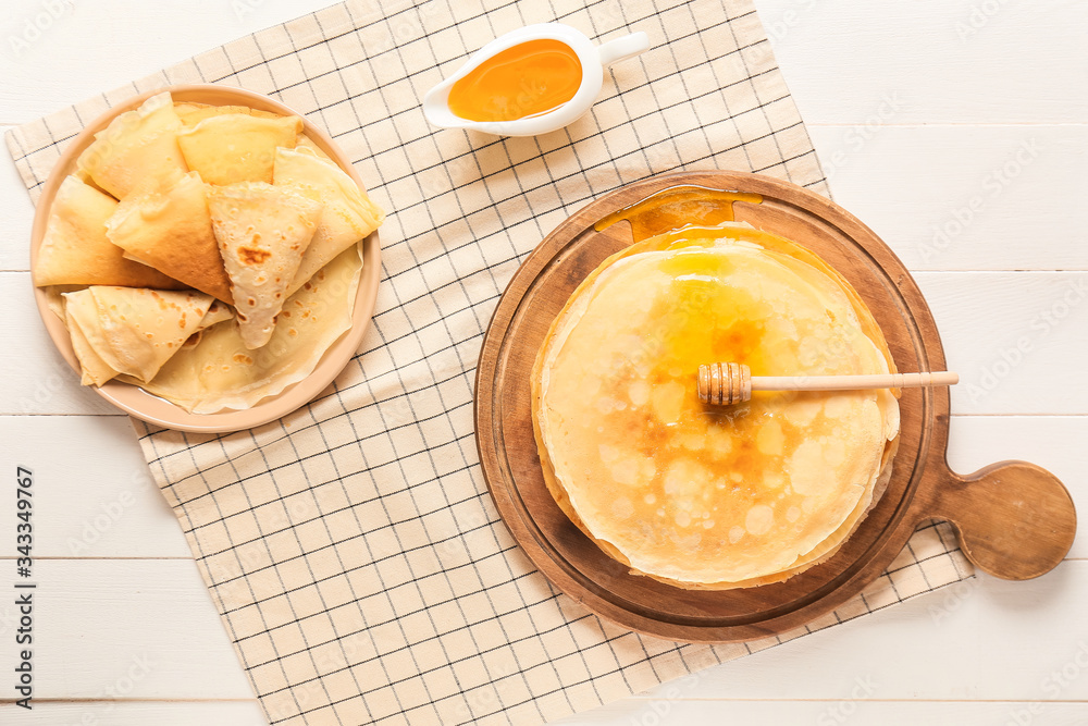 Tasty blini with honey on table