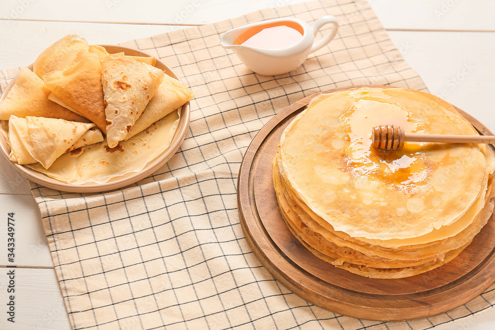 Tasty blini with honey on table