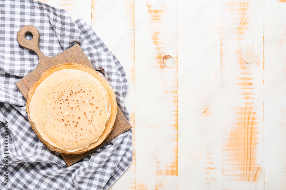 Board with tasty blini on table