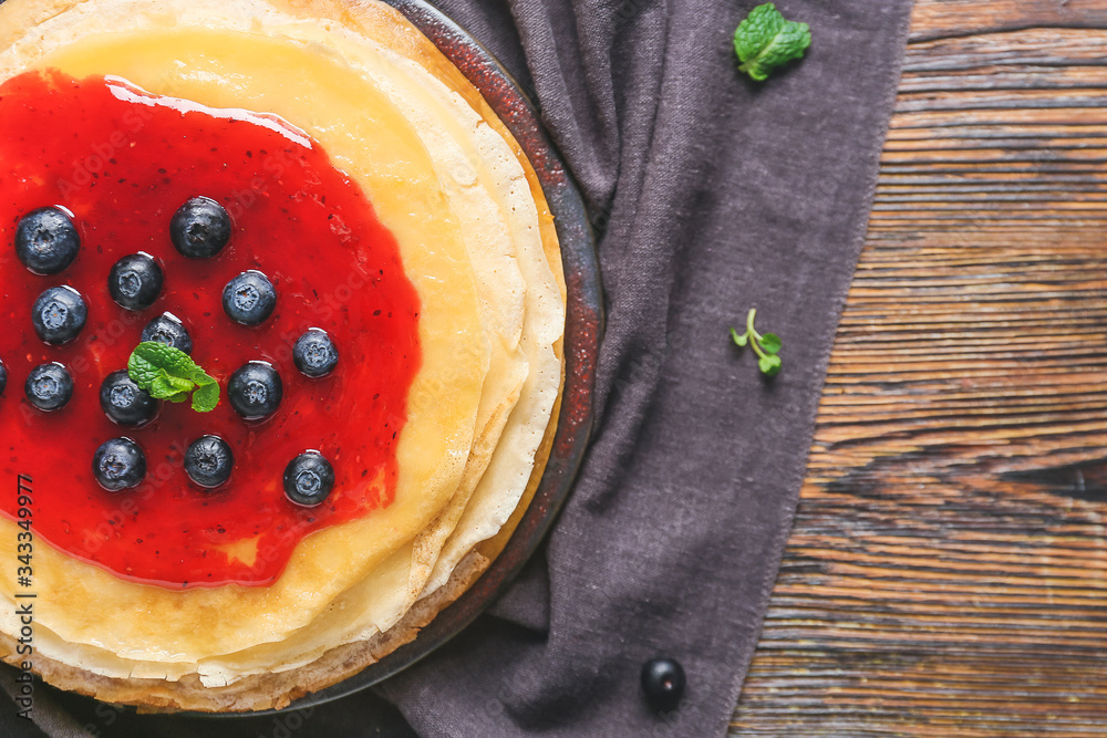 Tasty blini with berries on table