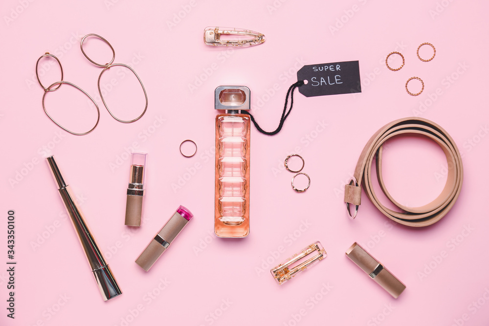 Bottle of perfume for sale with makeup cosmetics and accessories on color background