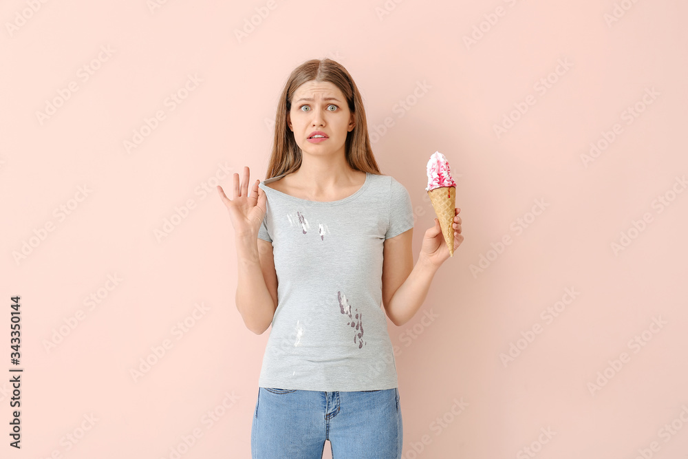 Troubled woman in dirty clothes eating ice-cream on color background