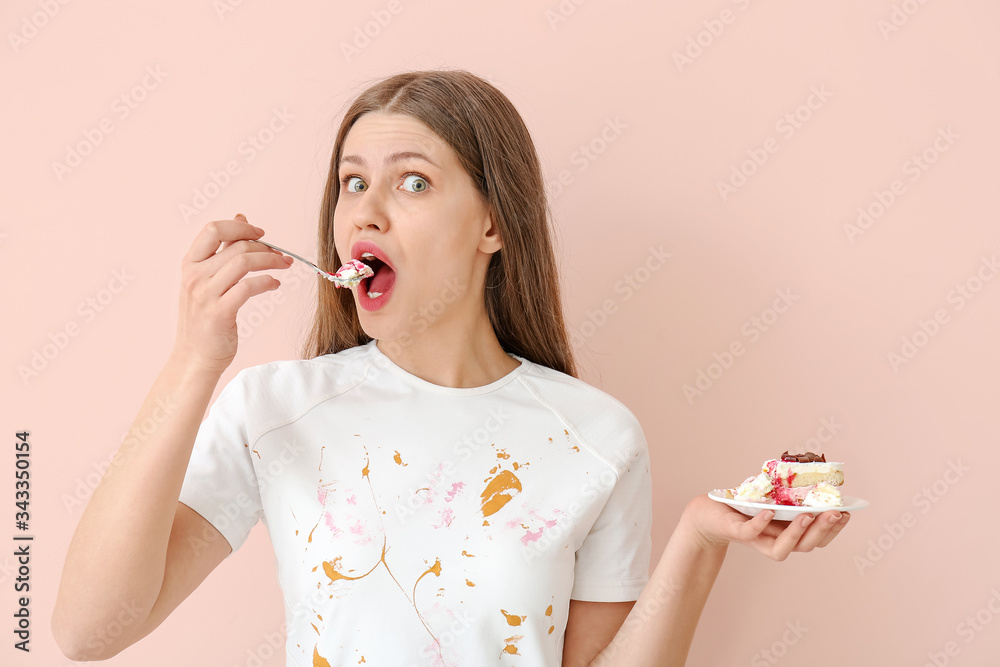 Woman in dirty clothes eating dessert on color background