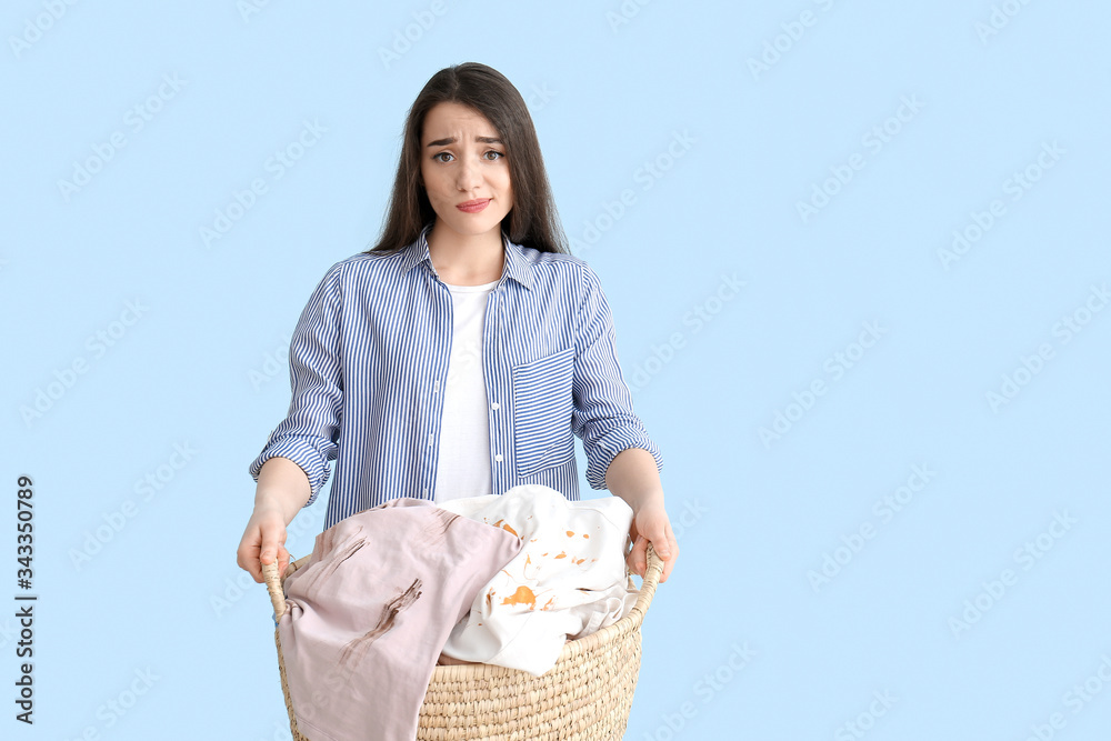 Displeased young woman with dirty clothes on color background