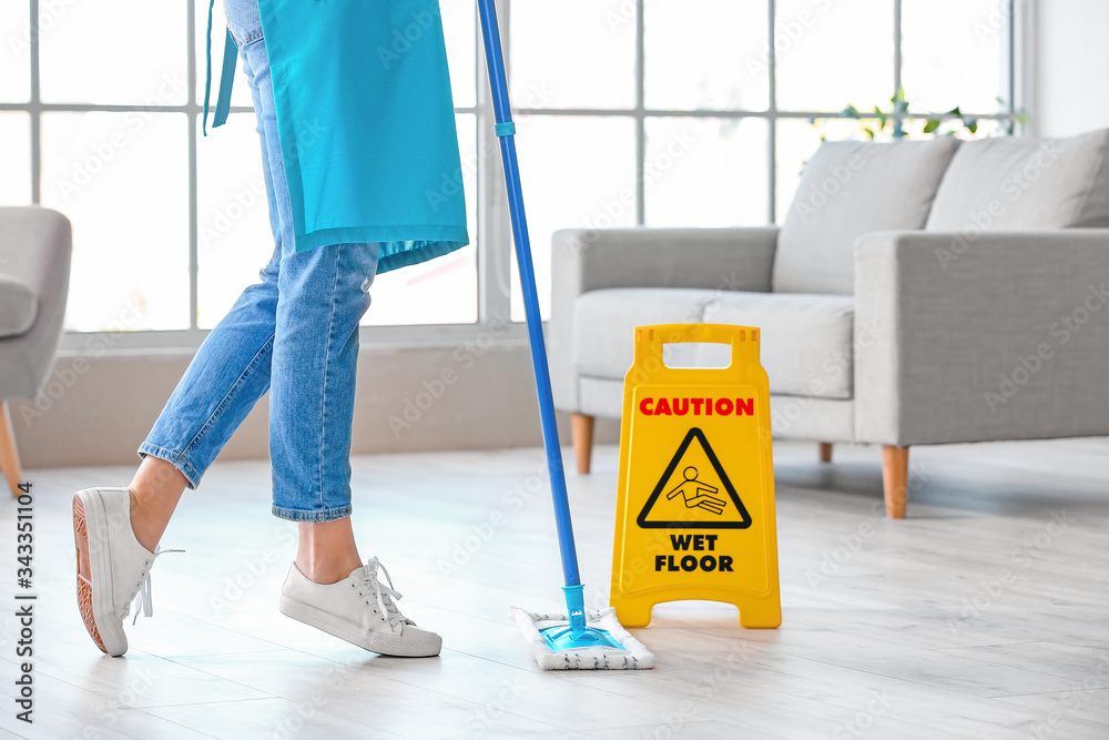 Young woman mopping floor in room