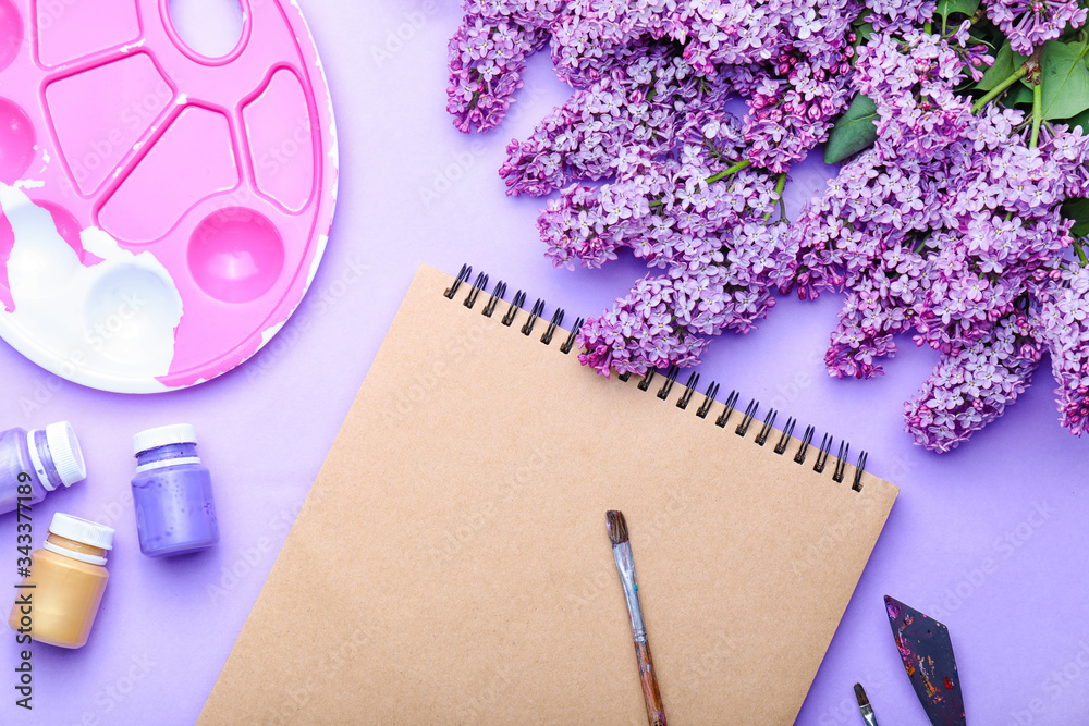 Beautiful lilac flowers and artists supplies on color background