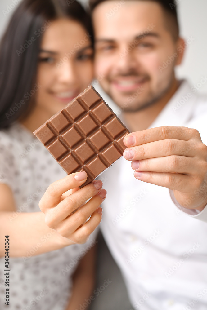 Beautiful young couple with chocolate at home, closeup