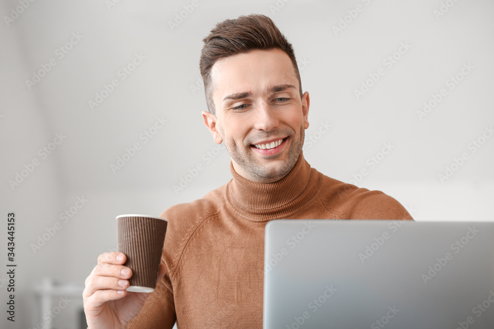 Young man drinking coffee while working in office