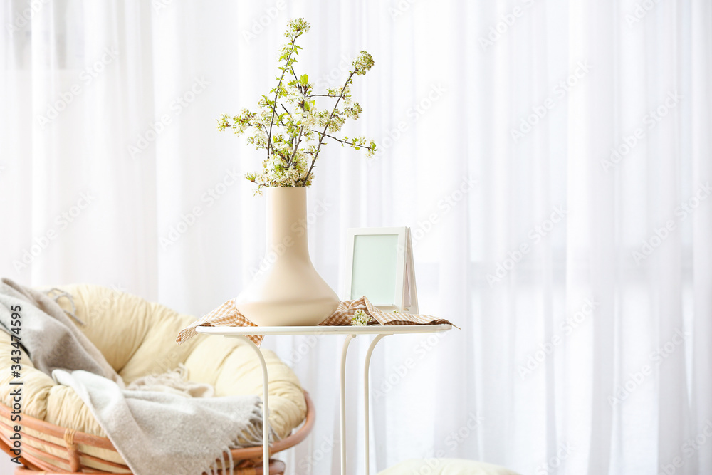 Vase with beautiful blooming branches on table in room