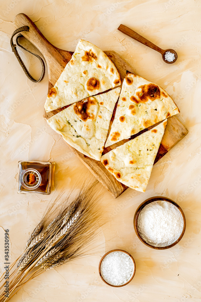 Focaccia ingredients. Wheat ears, flour, oil near bread on beige background top-down