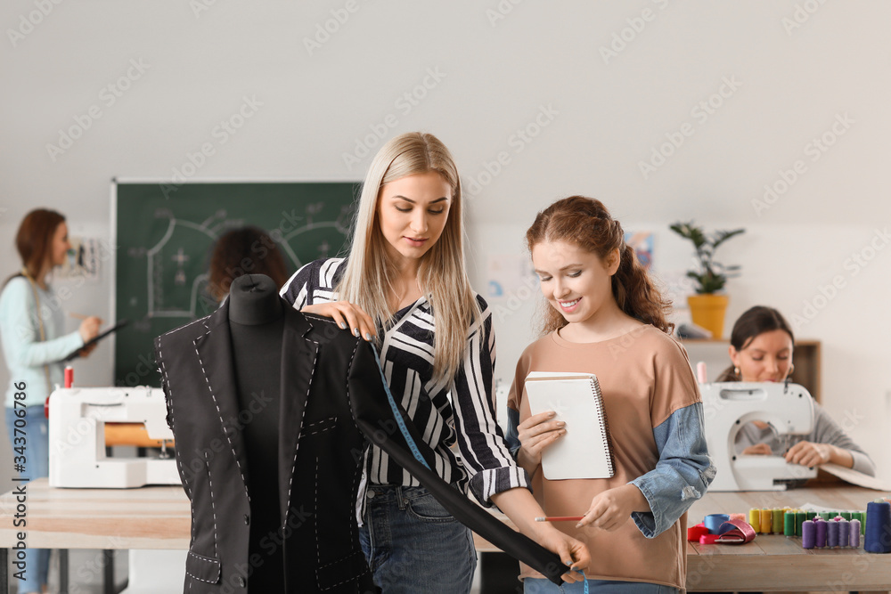 Young women near mannequin during tailors class in atelier