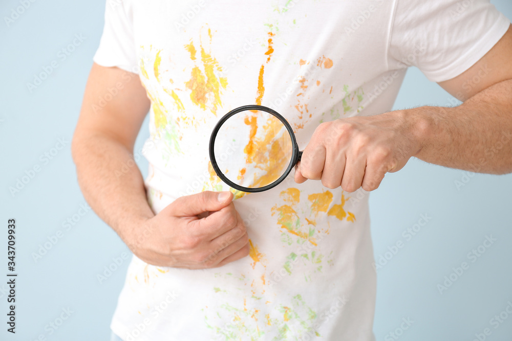 Man in dirty clothes and with magnifying glass on color background, closeup