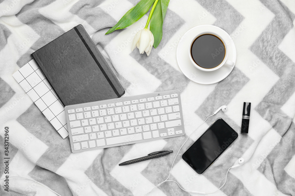 Composition with cup of coffee, PC keyboard, notebook, flower and mobile phone on plaid