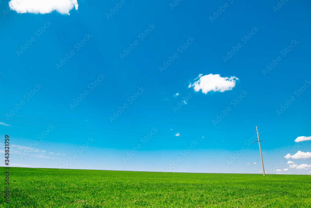 Meadow field with clouds and blue sky. Beautiful  minimal summer landscape of the hills.