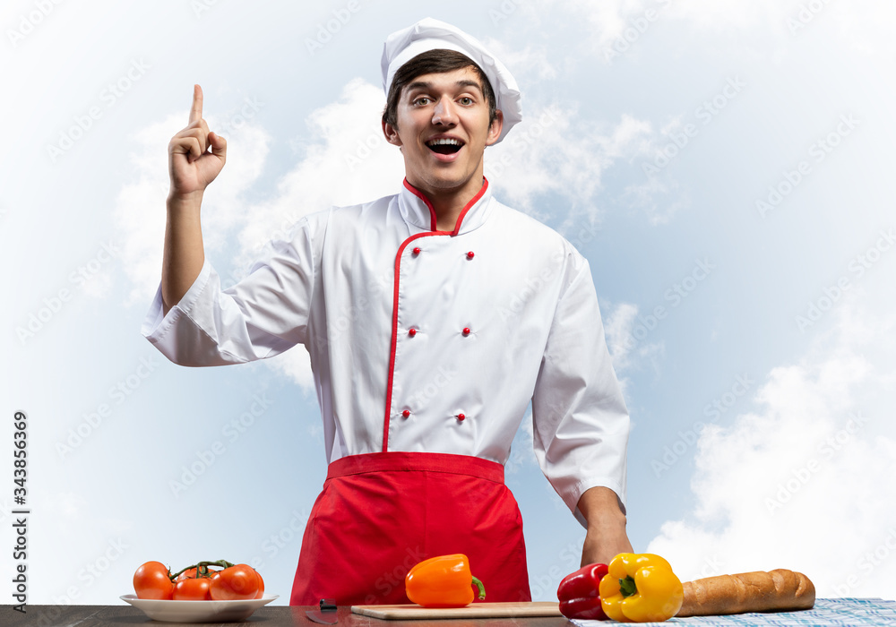 Young male chef standing near cooking table