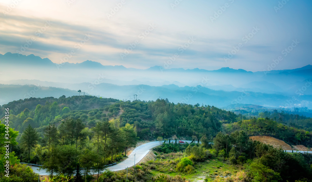 Mountain range with visible silhouettes through the morning colorful fog.