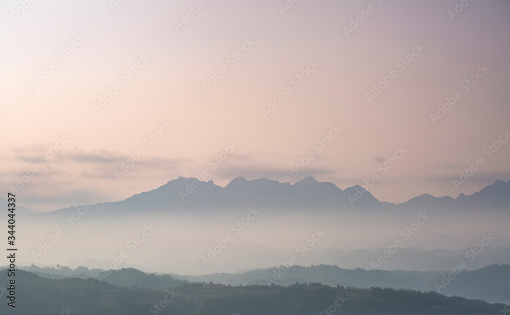 Mountain range with visible silhouettes through the morning colorful fog.