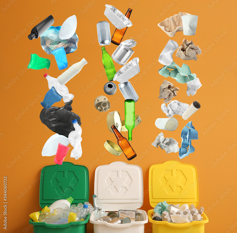 Garbage falling into containers near color wall. Recycling concept