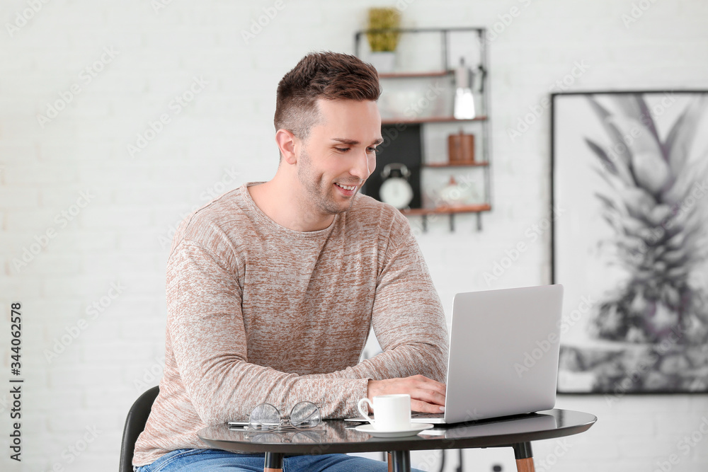 Young man drinking coffee while working on laptop in cafe