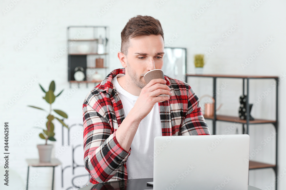 Young man drinking coffee while working on laptop in cafe