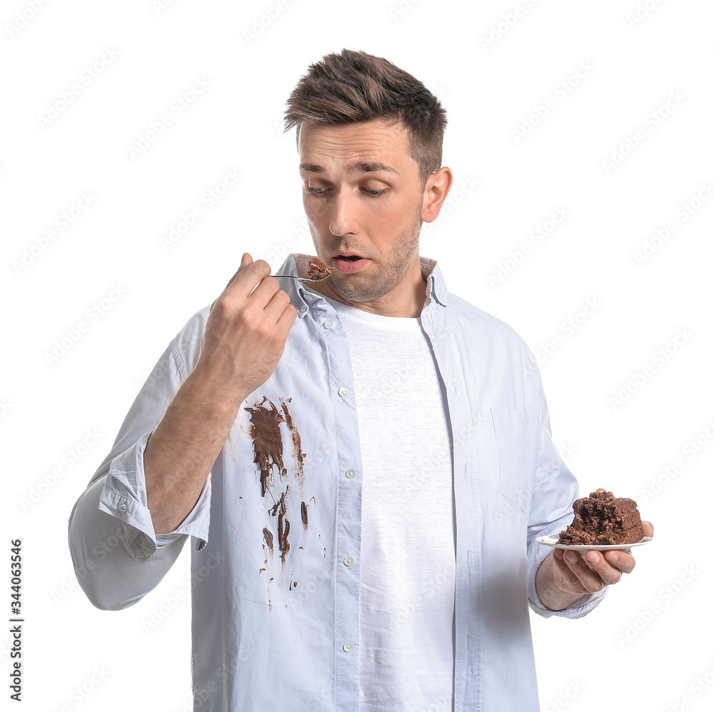 Troubled man in dirty clothes eating chocolate cake on white background