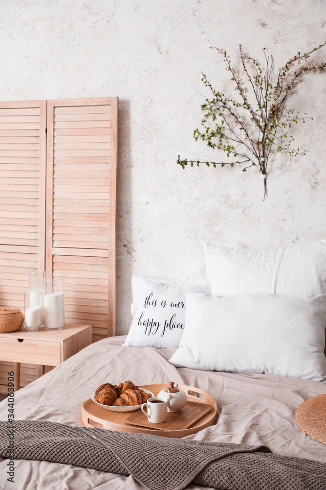 Interior of beautiful modern bedroom with breakfast and spring flowers