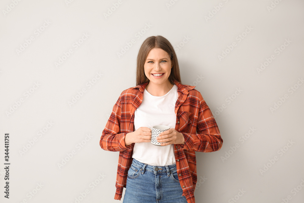 Young woman with coffee on light background