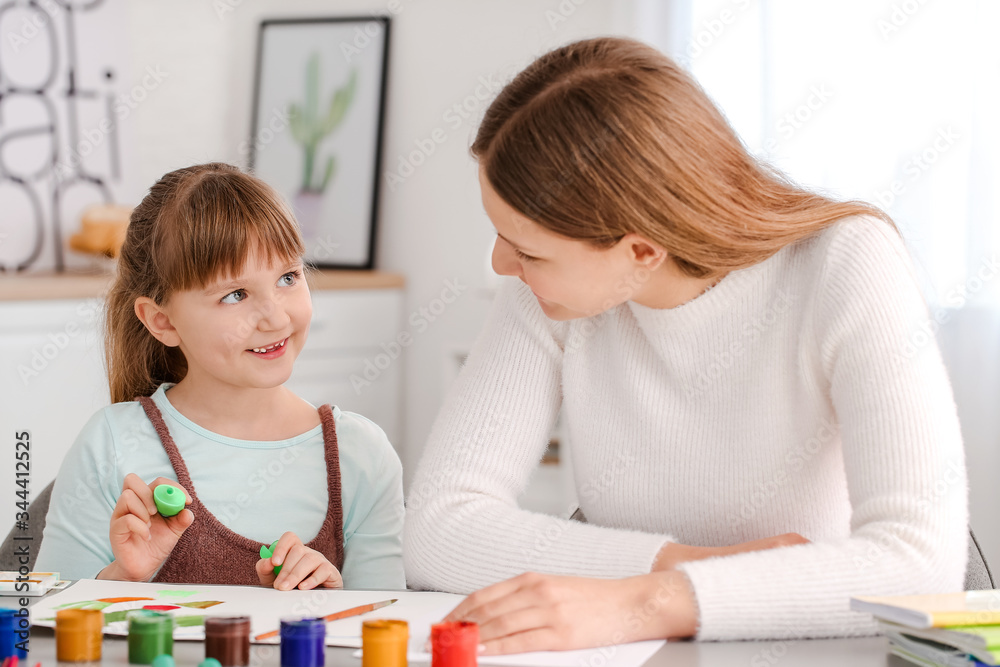 Drawing teacher giving private art lessons to little girl at home